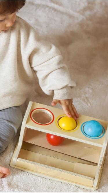 Child playing with a SENSORY wooden toy on a soft surface