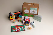 Collection of educational toys and materials with a Montessori box on a neutral background suitable for a baby aged 3-4 months