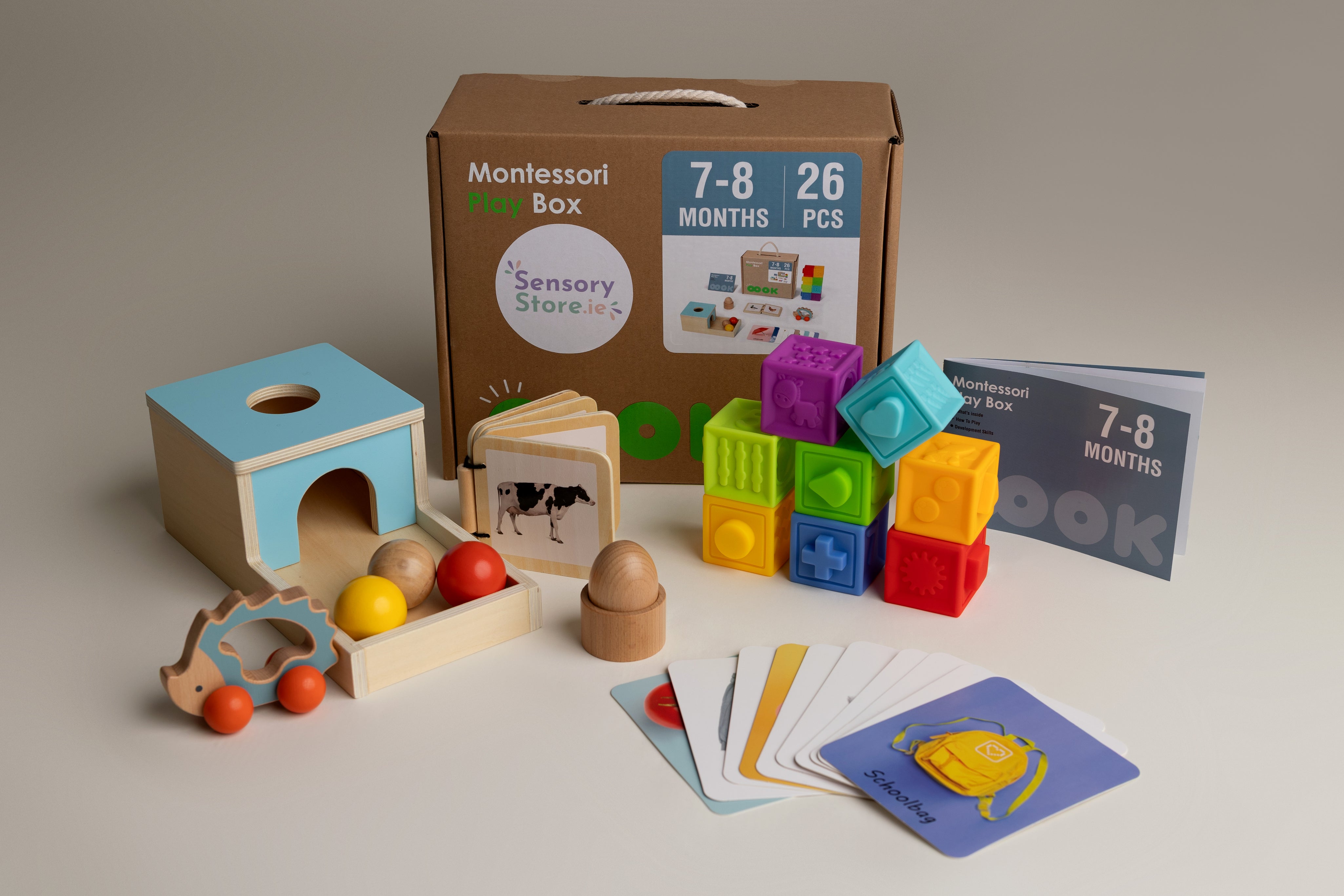 Montessori play box with educational toys and materials on a neutral background for a baby aged 7-8 months
