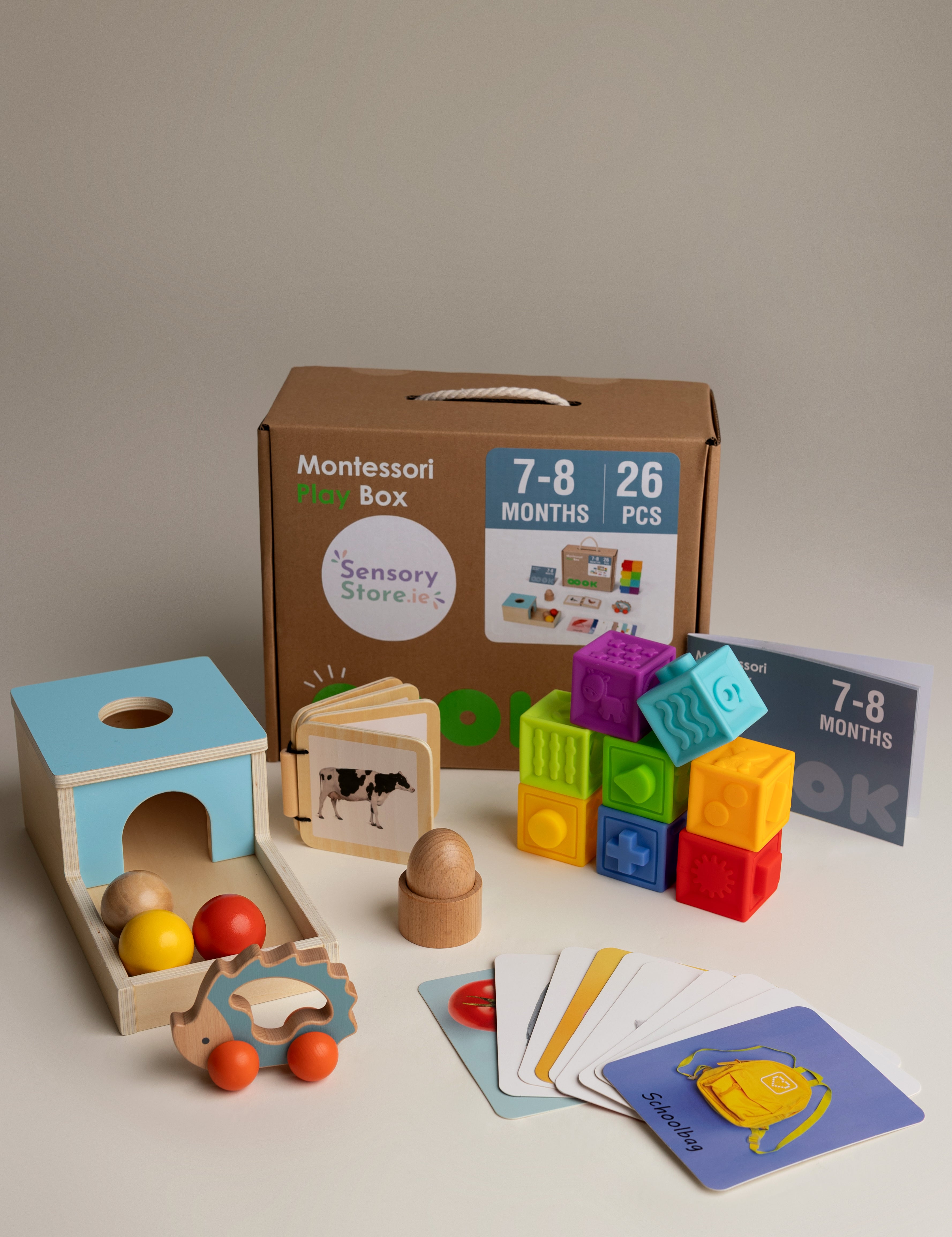 Collection of educational toys and books for infants aged 7-8 months on a neutral background