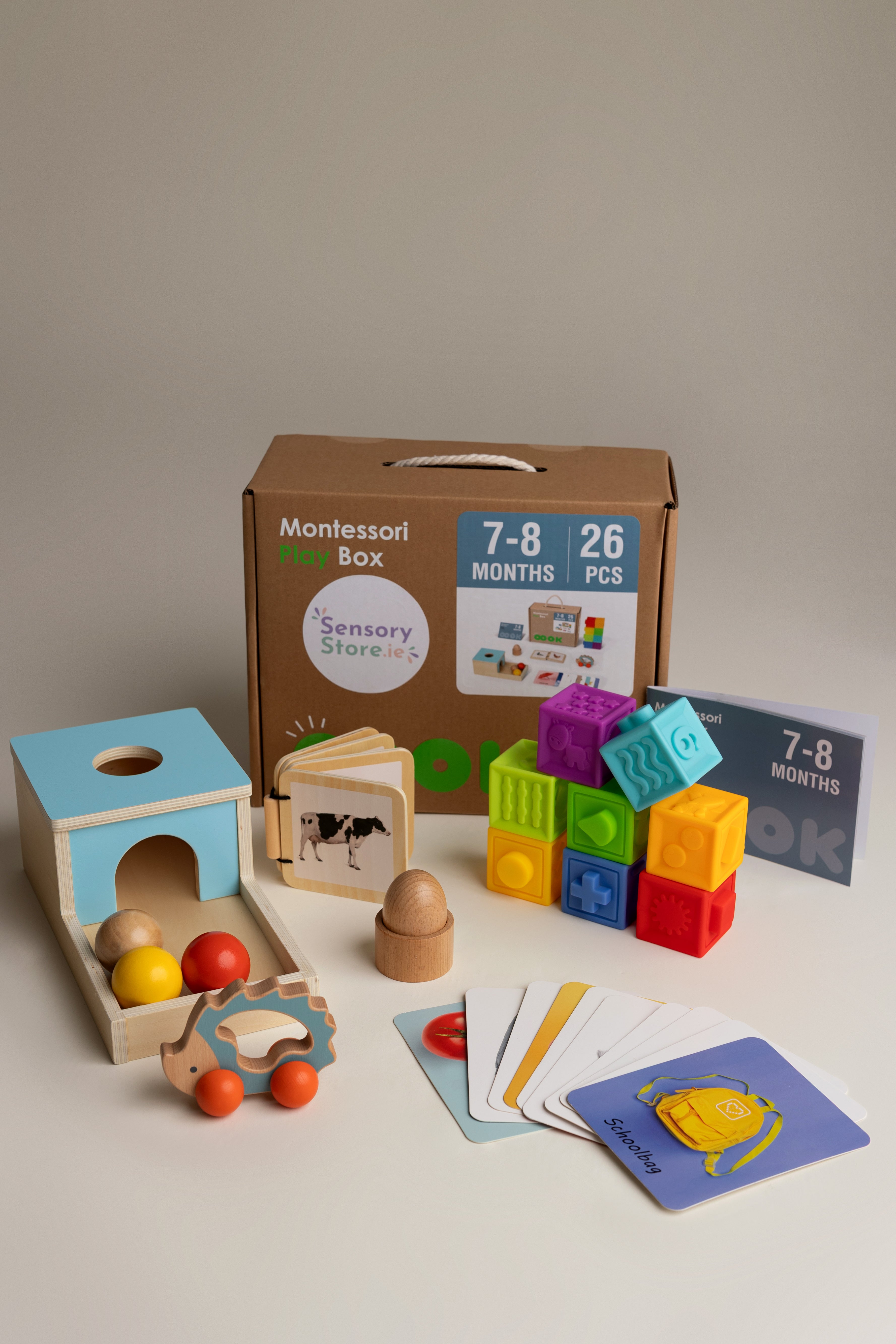 Collection of educational toys and books for infants aged 7-8 months on a neutral background