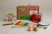 Montessori music play box with toys and books on a neutral background