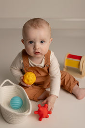Baby playing with colorful toys on a neutral background