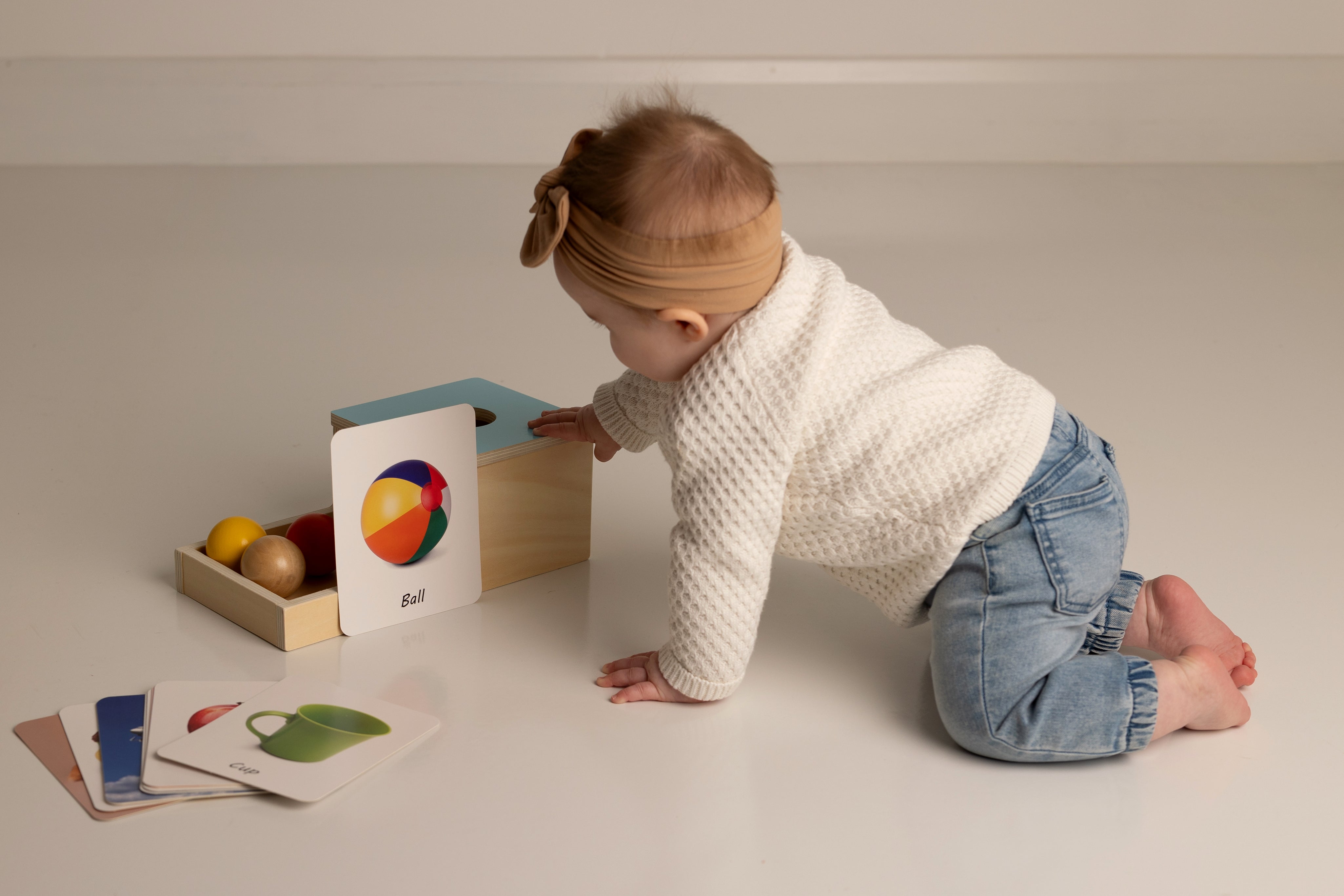 Baby playing with educational toys on a light-colored floor.