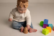 Baby playing with colorful blocks on a plain background