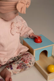 Child playing with a colorful wooden toy set on a neutral background
