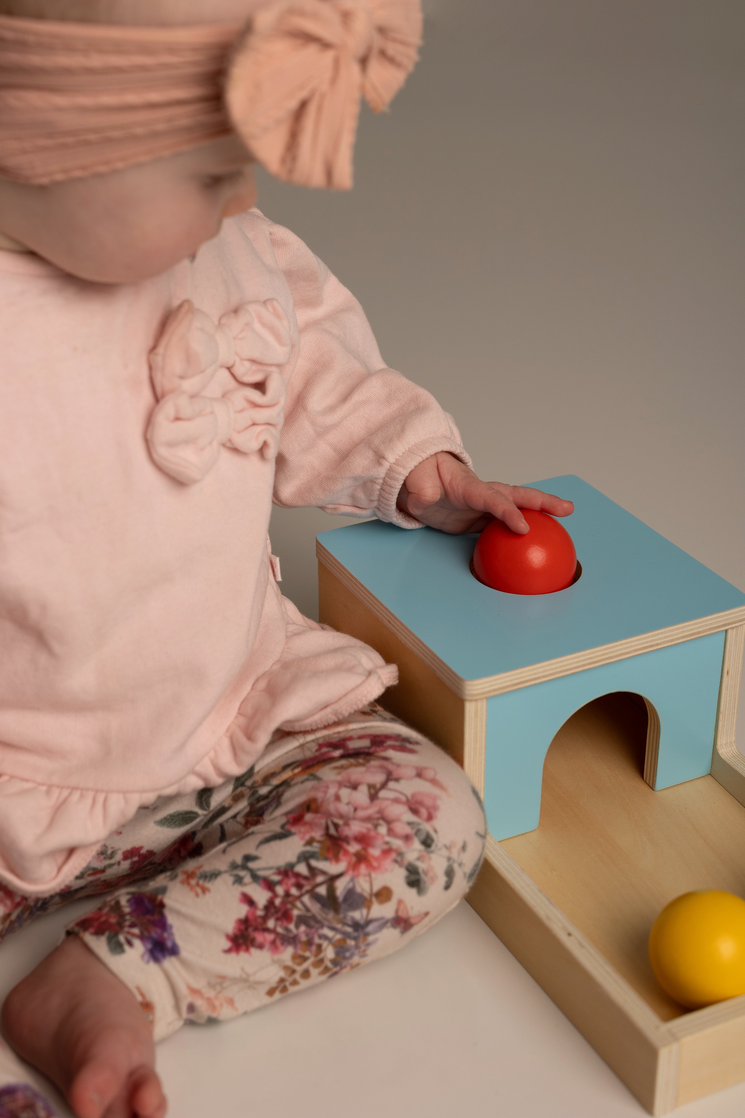 Child playing with a colorful wooden toy set on a neutral background