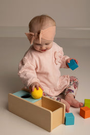 Baby playing with colorful blocks on a neutral background