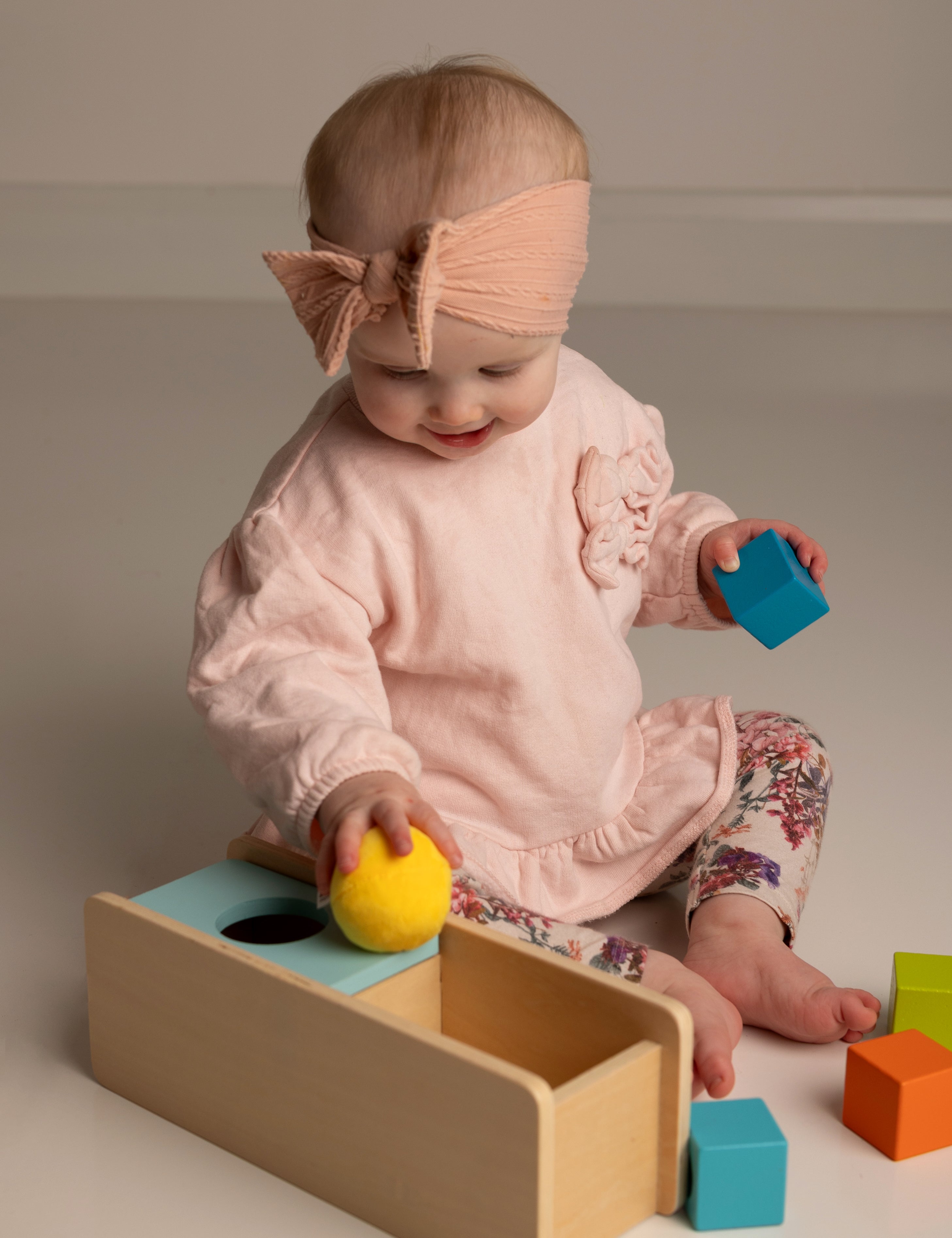 Baby playing with colorful blocks on a neutral background
