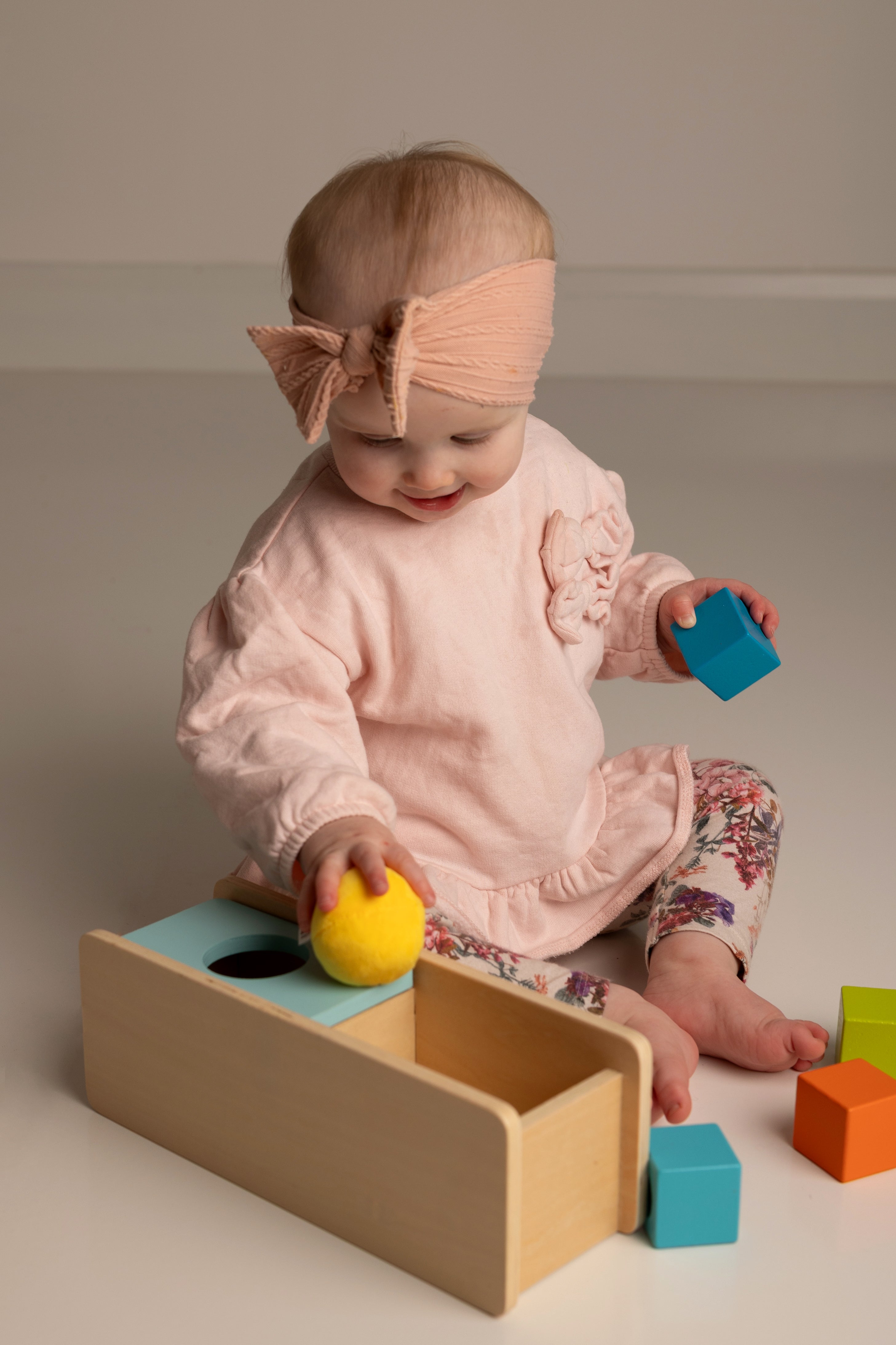 Baby playing with colorful blocks on a neutral background