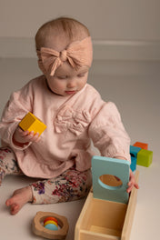 Baby playing with colorful wooden toys on a plain background