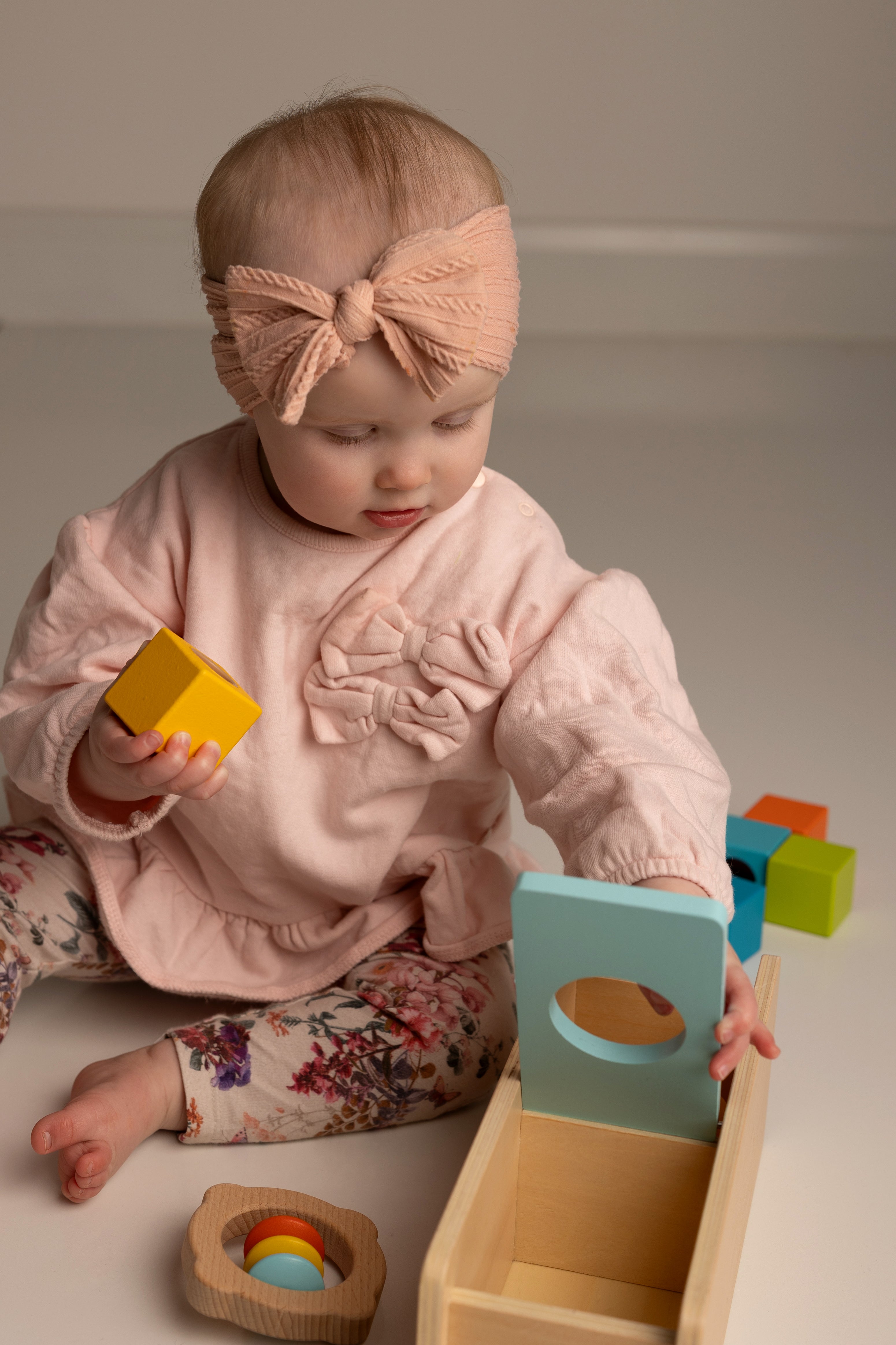 Baby playing with colorful wooden toys on a plain background