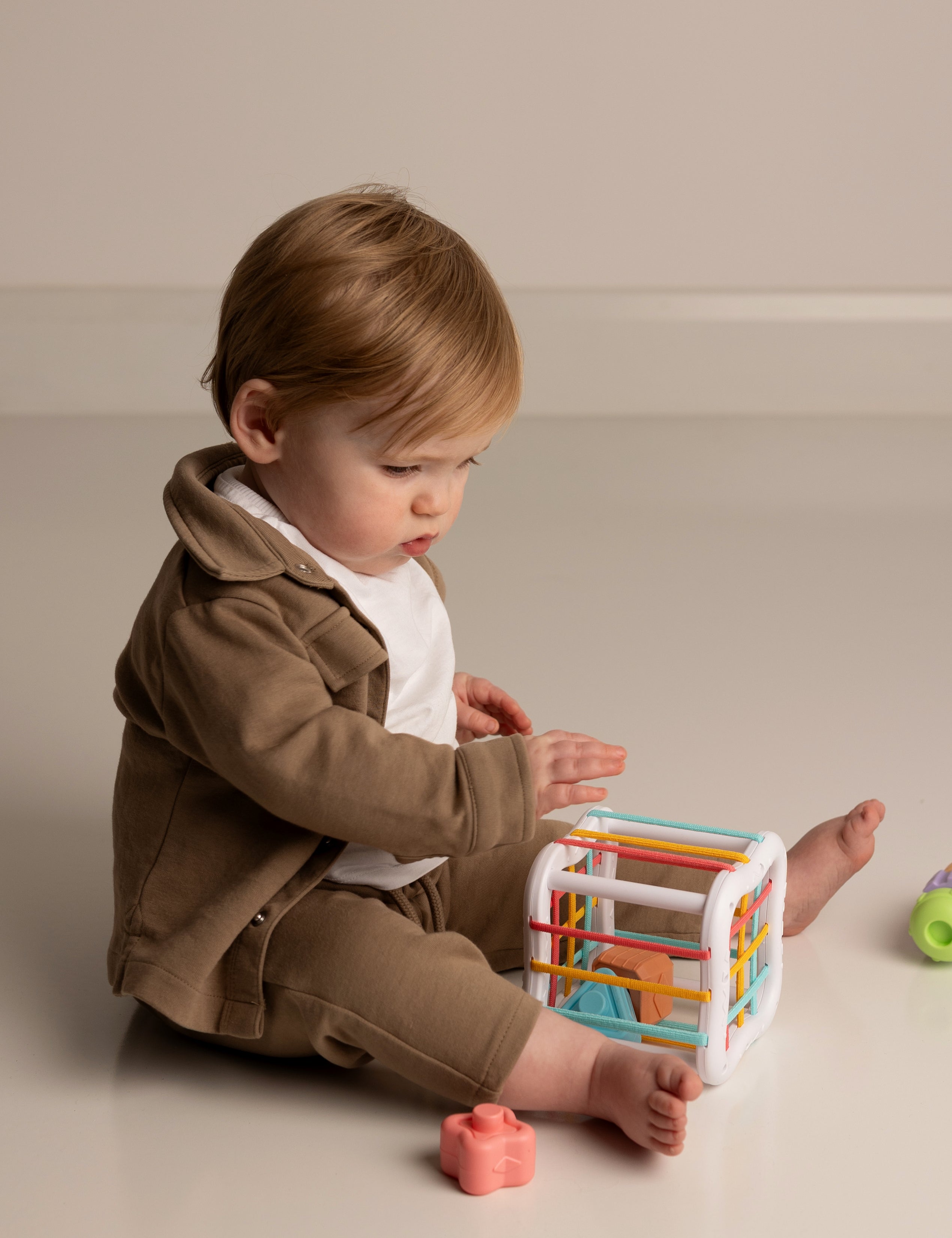 Child playing with a colorful toy on a plain background