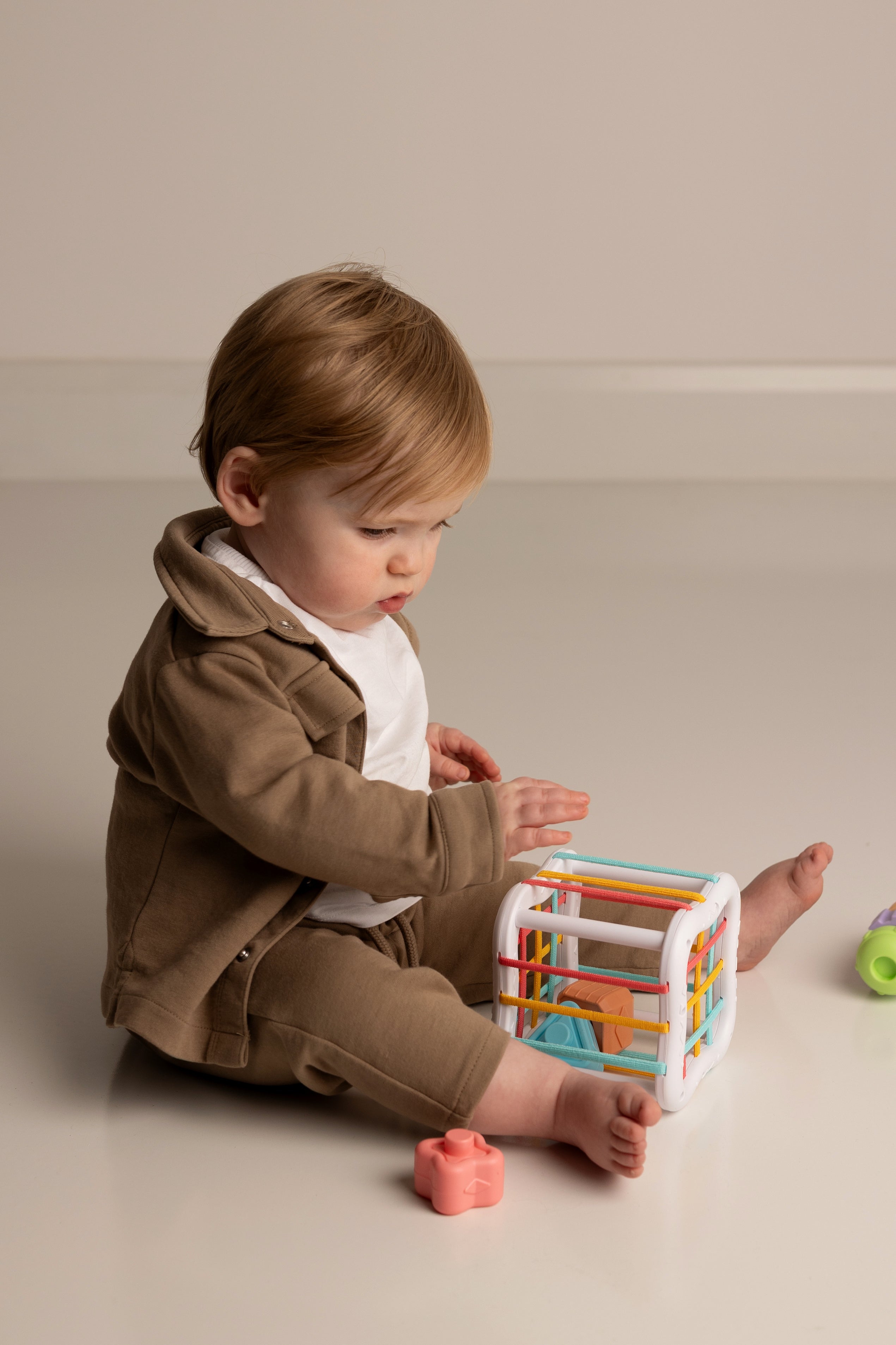 Child playing with a colorful toy on a plain background
