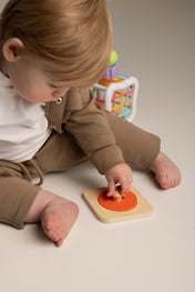 Child playing with a wooden toy on a neutral background