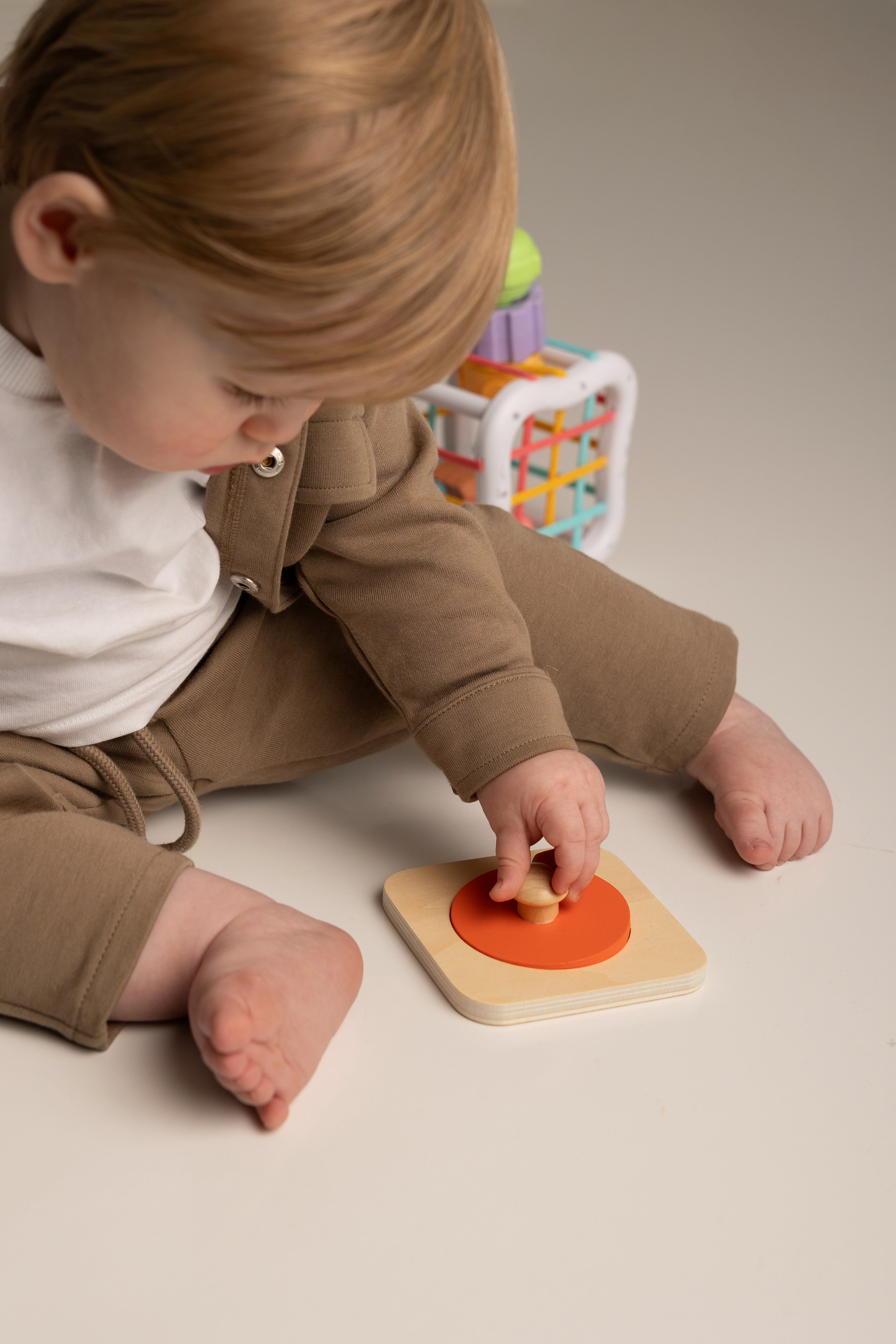 Child playing with a wooden toy on a neutral background