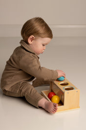 Child playing with a wooden push ball set on a plain background