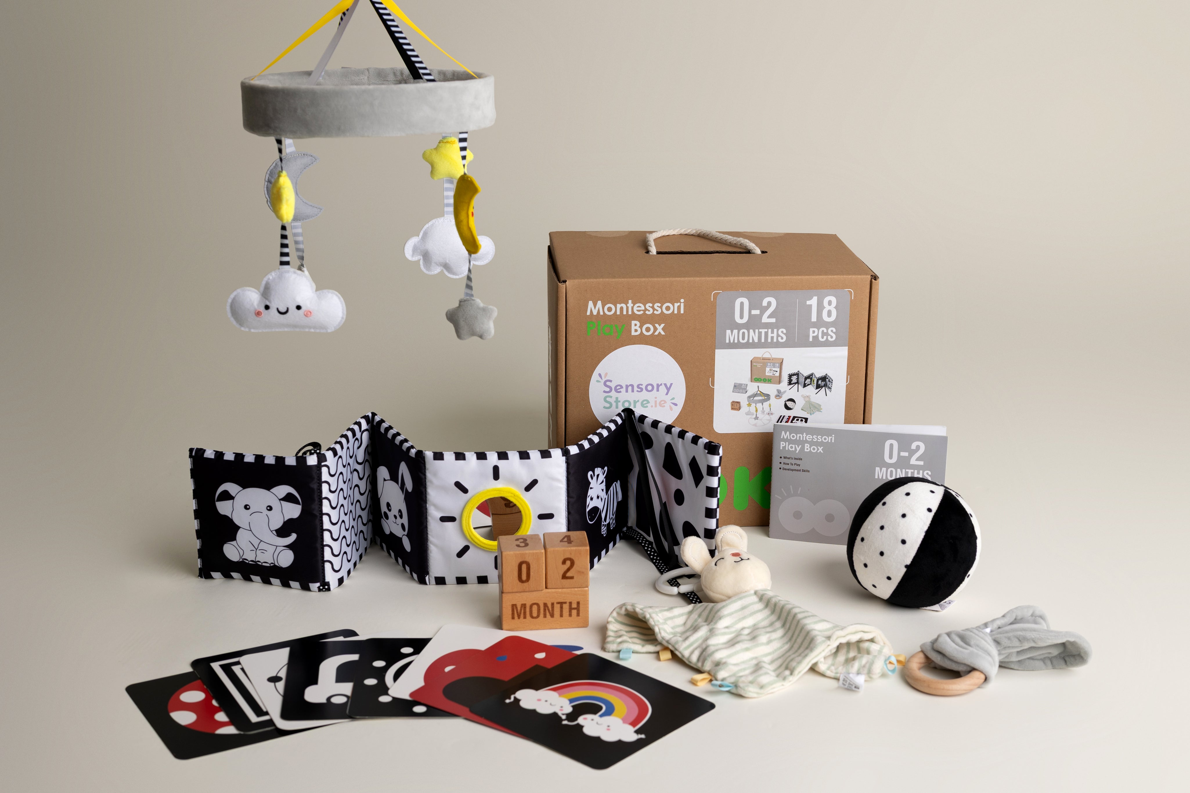 Collection of black and white baby toys and educational items on a neutral background suitable for a baby aged 0-2 months