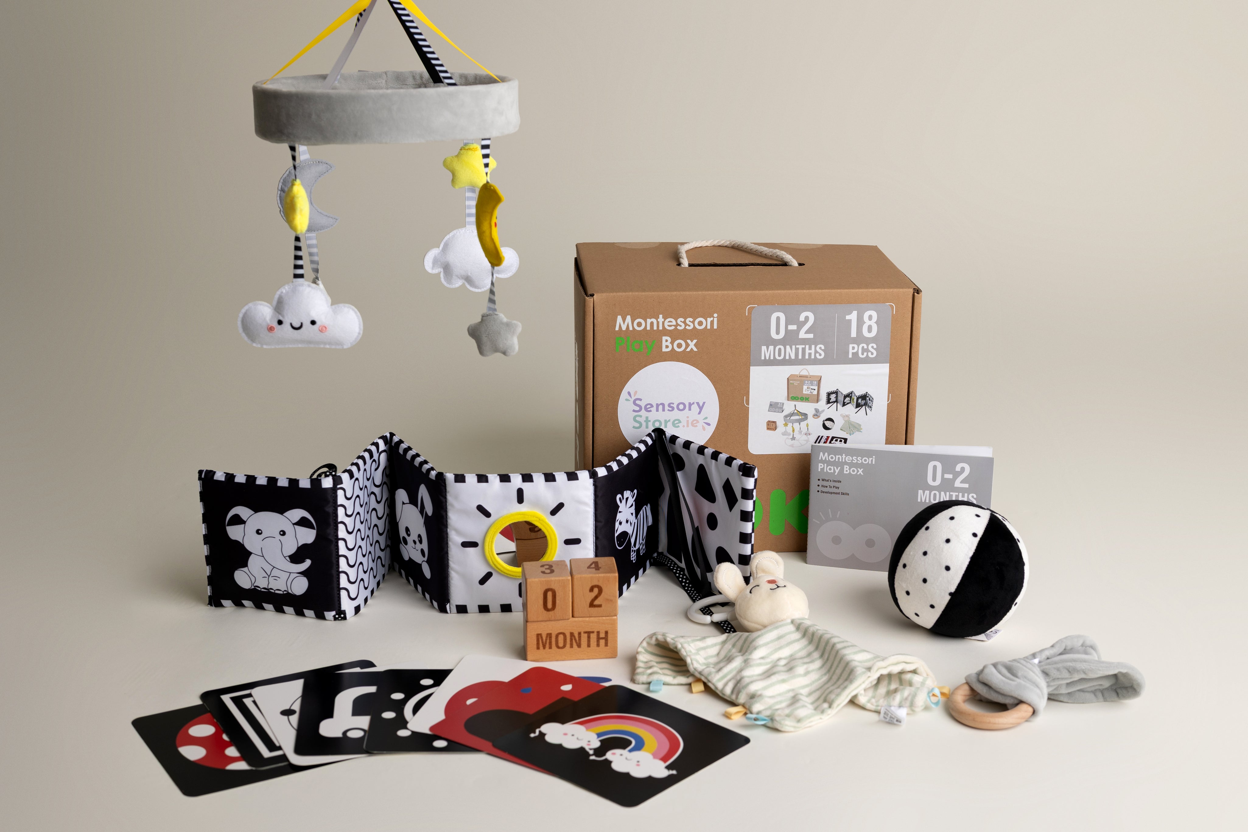 Collection of black and white baby toys and educational items on a neutral background suitable for a baby aged 0-2 months